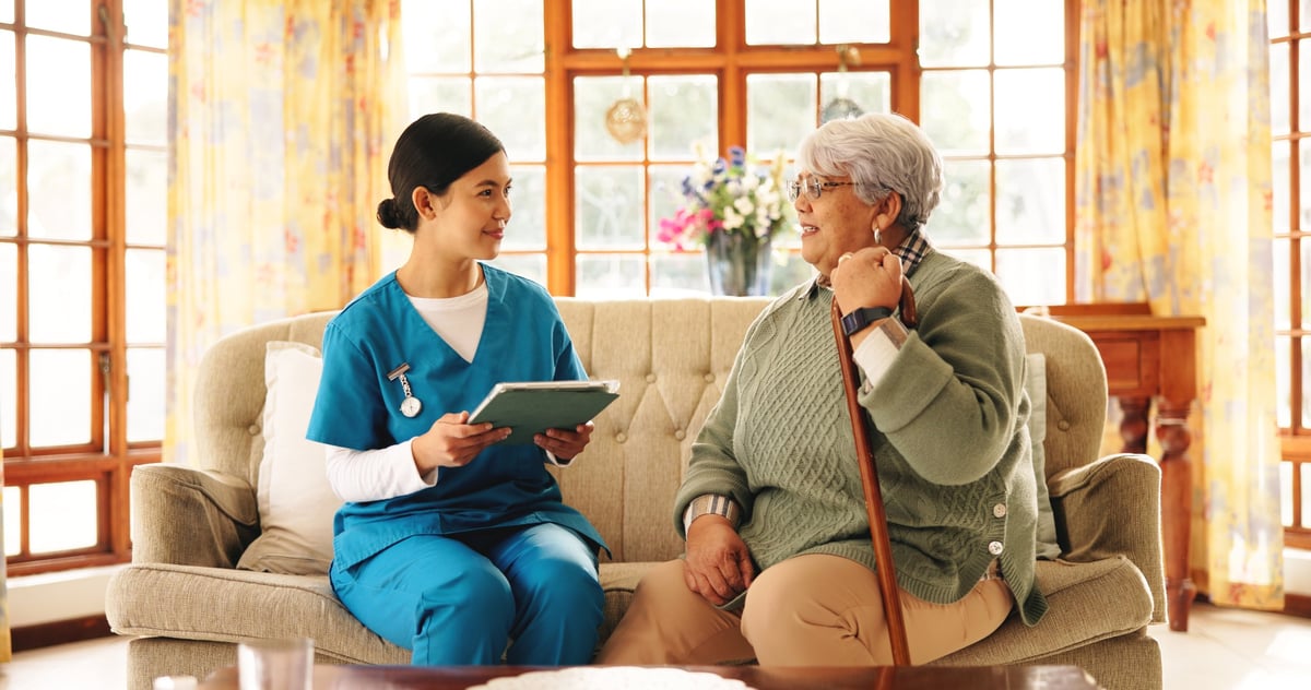 Senior woman with caregiver reviewing healthcare documents on tablet